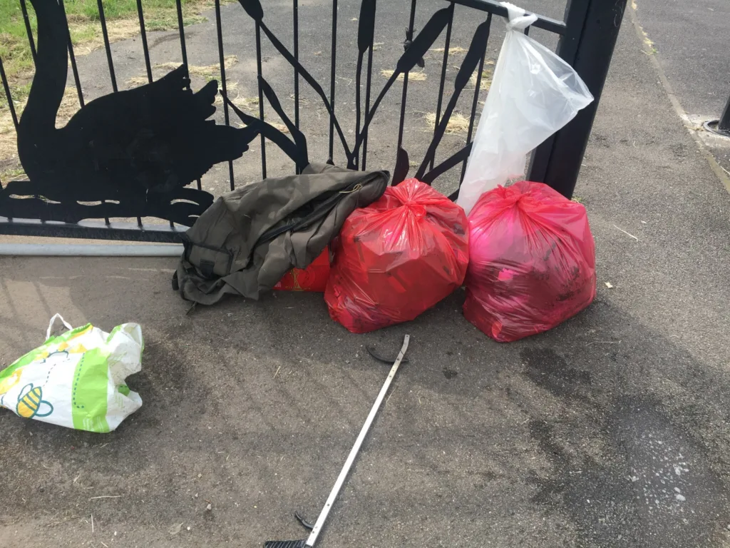 FixMyStreet upload from resident and the accompanying comment: 2 red bags by the gate at the bottom of the fleet fishing bag a couple other bits