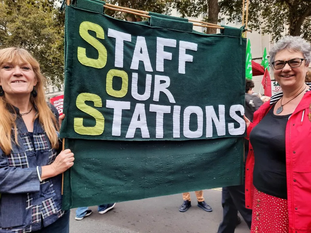 Staff our Stations - Two women on the march with their banner. On Thursday, an estimated 1,000 people – one for every ticket office facing closure - marched for the cause. 