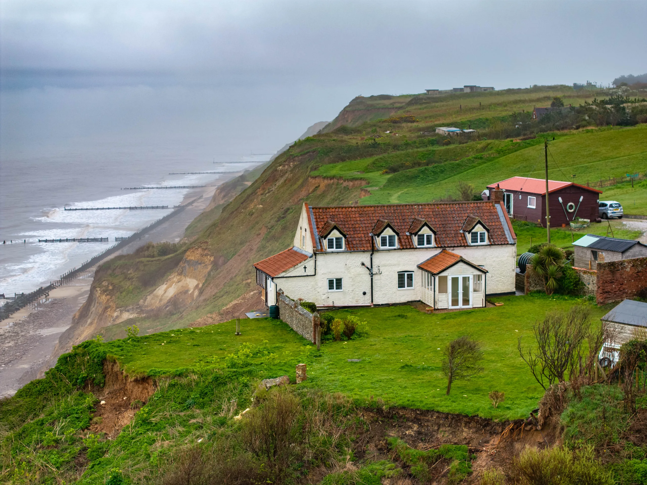 Shocking photos taken today (Thurs) show a three-bedroom house hanging perilously over a cliff edge on the north Norfolk coast after a surge of recent cliff falls. , Trimingham, Norwich Thursday 04 April 2024. Picture by Terry Harris